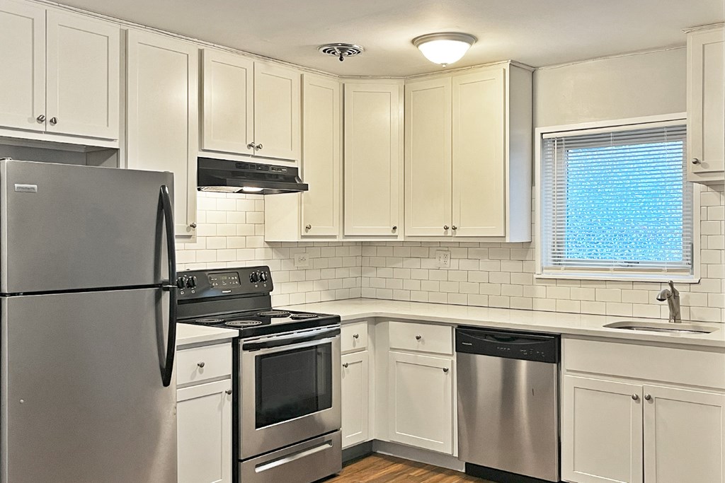 A kitchen with white cabinets and a stainless steel refrigerator.