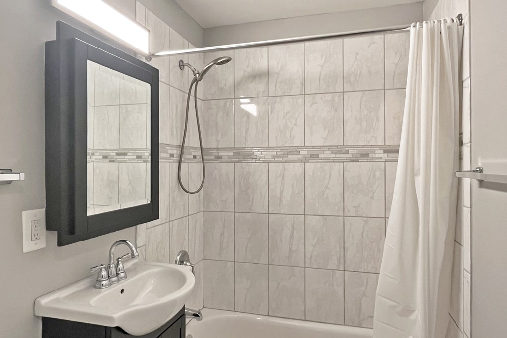 A bathroom with a white sink and a shower with a white curtain.