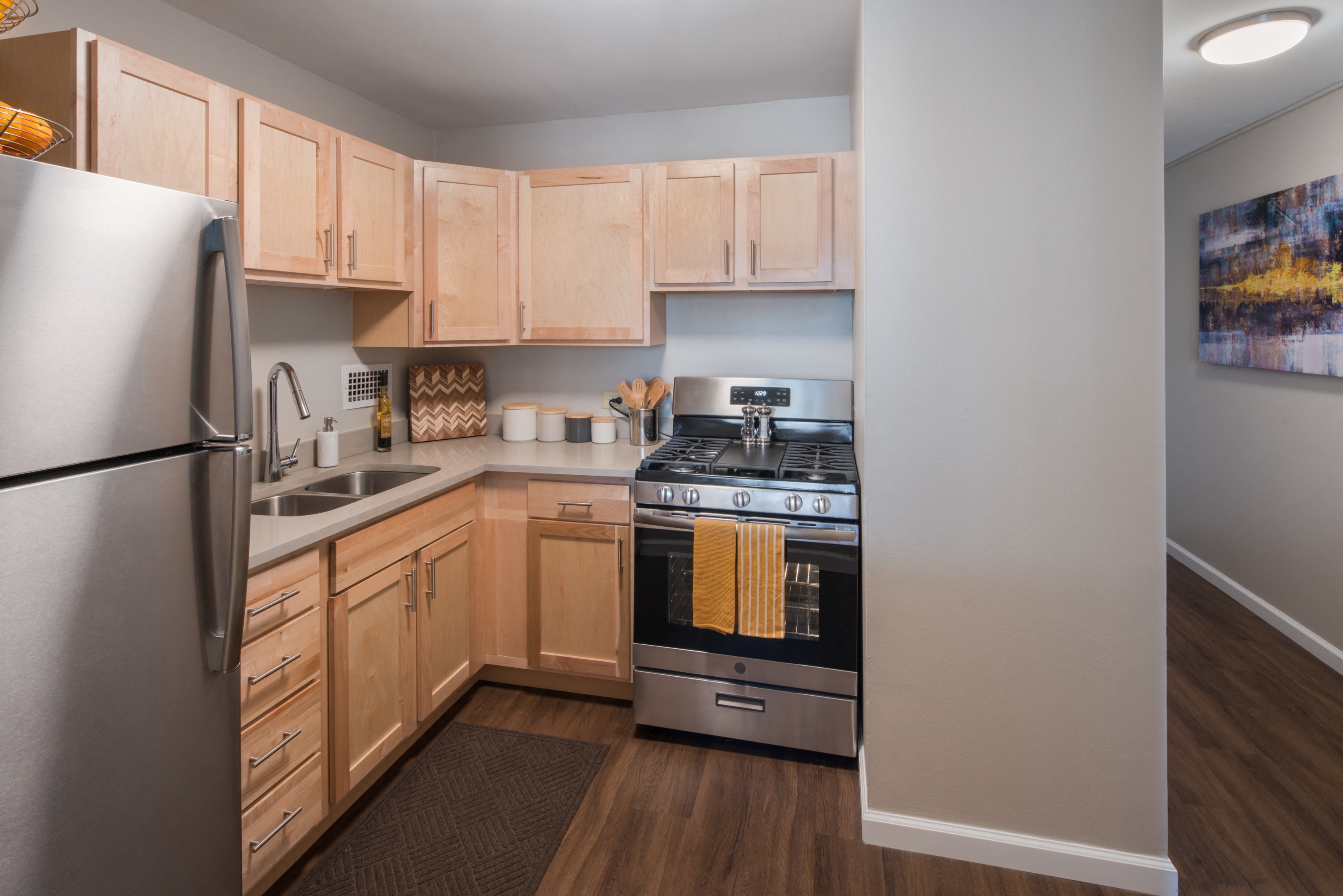 Kitchen with stainless steel appliances, light wood cabinetry, and plan flooring at Eden Commons, Chicago, IL