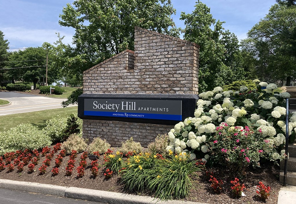 a sign apartments in front of a flower garden
