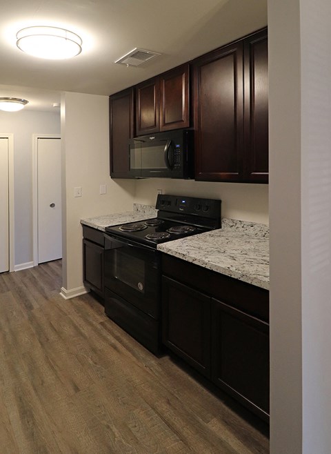 a kitchen with dark wood cabinets and granite counter tops and a stove and microwave