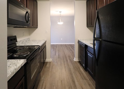 an empty kitchen with black appliances and wood flooring
