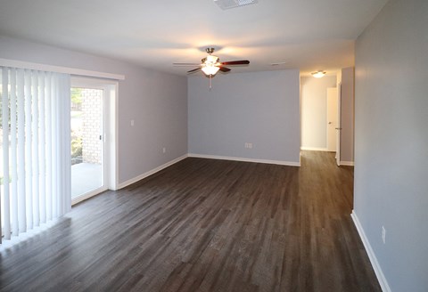 an empty living room with wood floors and a ceiling fan