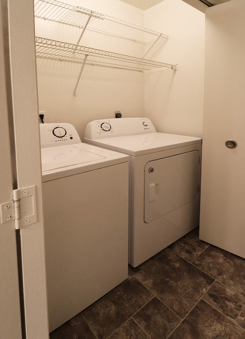 a washer and dryer in a laundry room with a shelf above the door