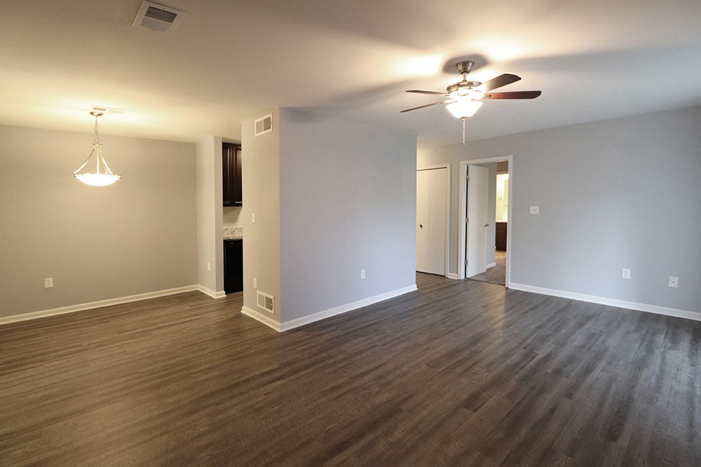 an empty living room with wood floors and a ceiling fan