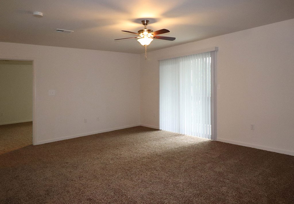 an empty living room with a ceiling fan and a window