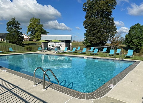 a resort style pool with blue chairs and a white house