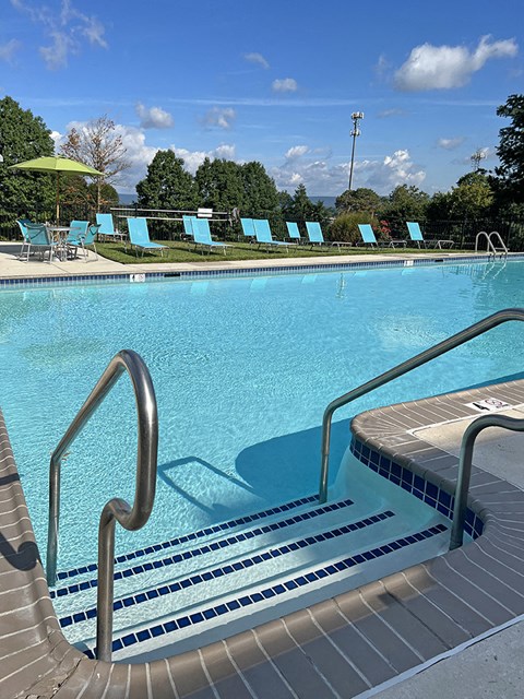 a large pool of water with blue chairs and a umbrella