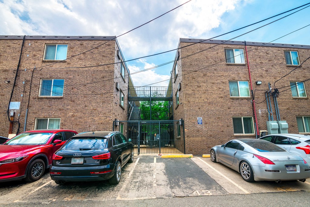 a parking lot between two brick buildings with cars parked
