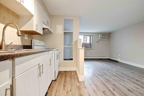 an empty kitchen and living room with white cabinets
