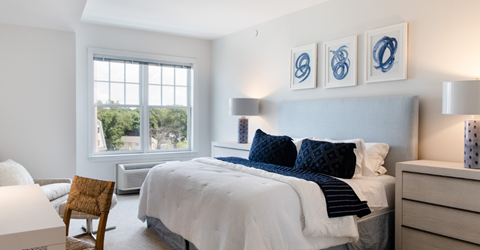 A bedroom with a bed, chair, and pictures on the wall.