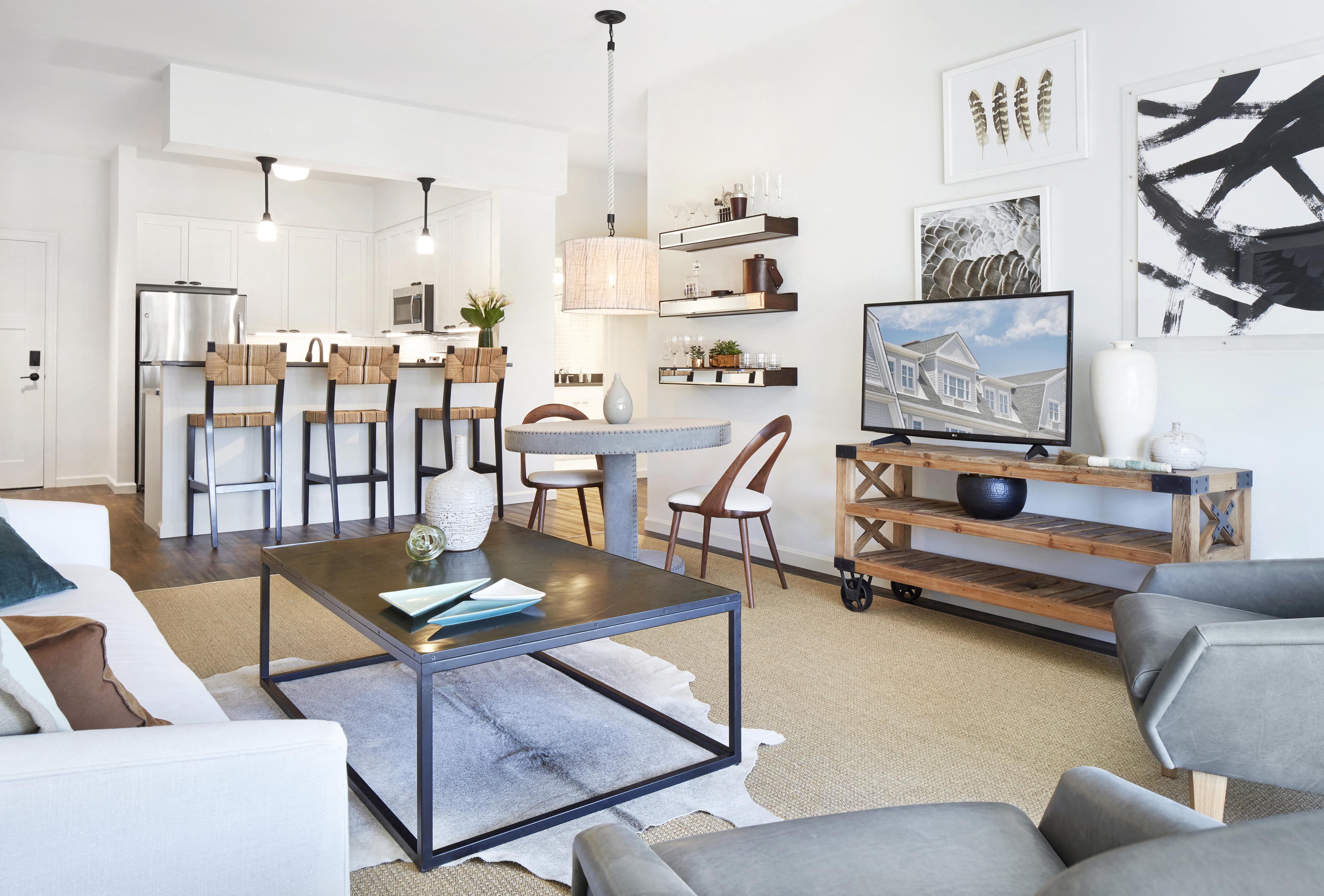 A modern living room with a glass coffee table and grey couches.