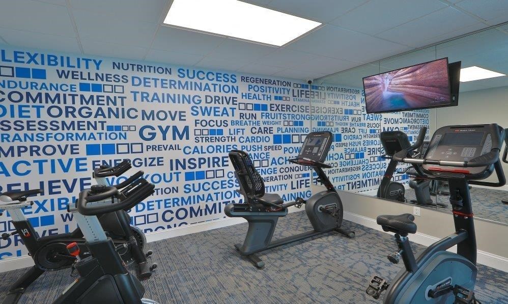 a gym with exercise equipment and a wall with words