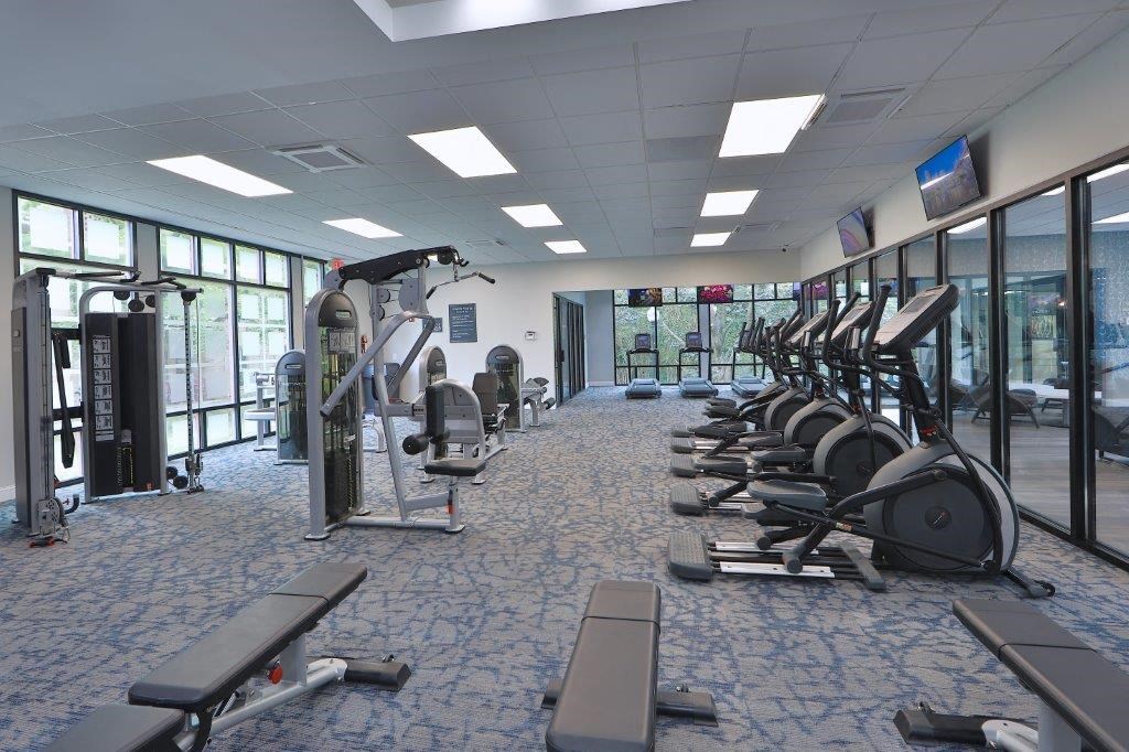 a gym with cardio equipment and windows in a building