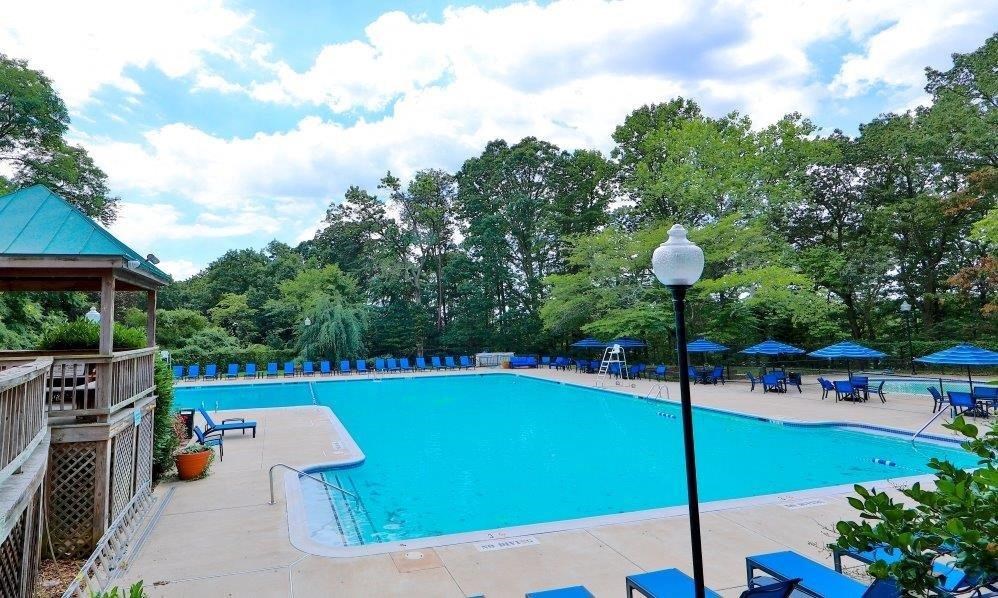 a large blue swimming pool with chairs and umbrellas