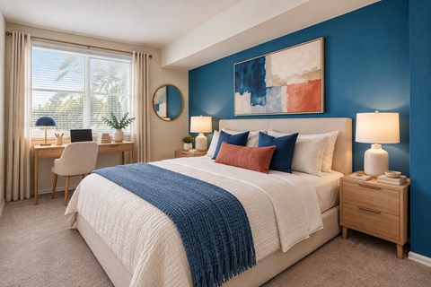 A bedroom with a large bed and a desk with a chair.