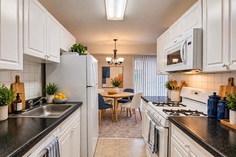 A kitchen with white cabinets and black countertops.