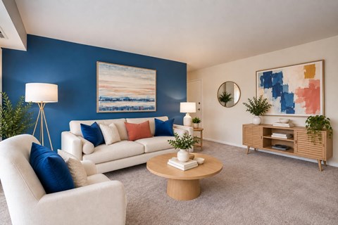 A living room with a white sofa, a wooden coffee table, and a painting on the wall.