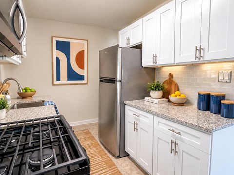 A modern kitchen with a stainless steel refrigerator and white cabinets.