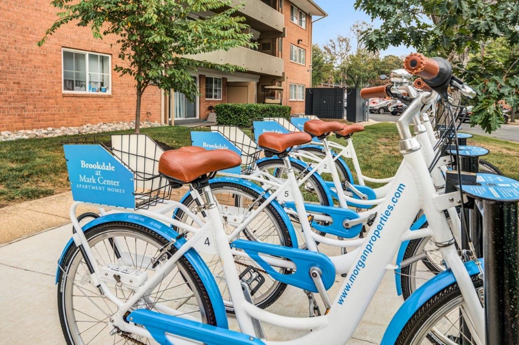 a group of blue and white bikes parked on a sidewalk