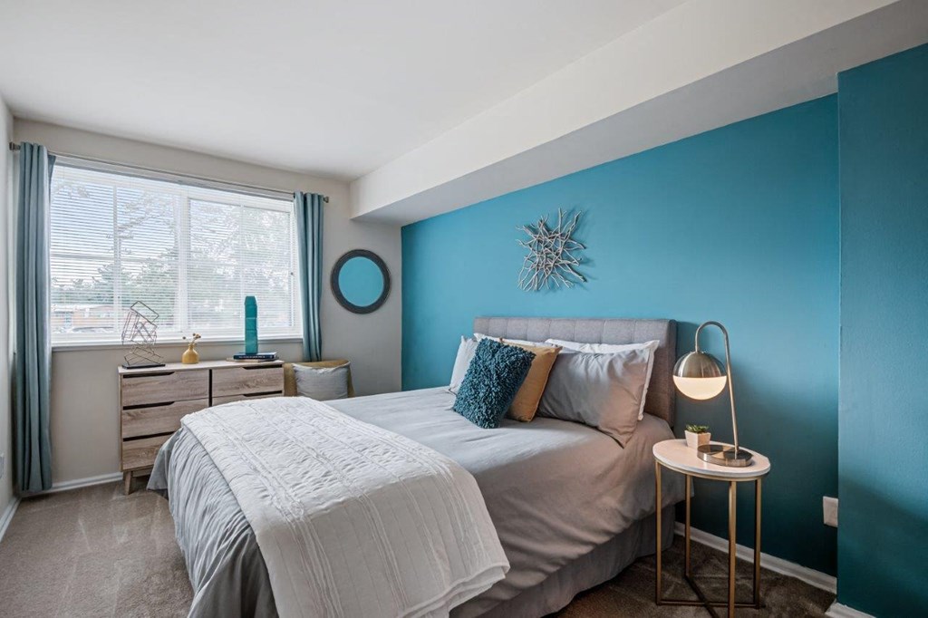 a bedroom with a bed and a blue wall and a window