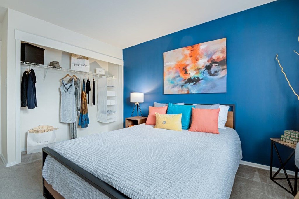 a bedroom with a blue wall and a bed with colorful pillows
