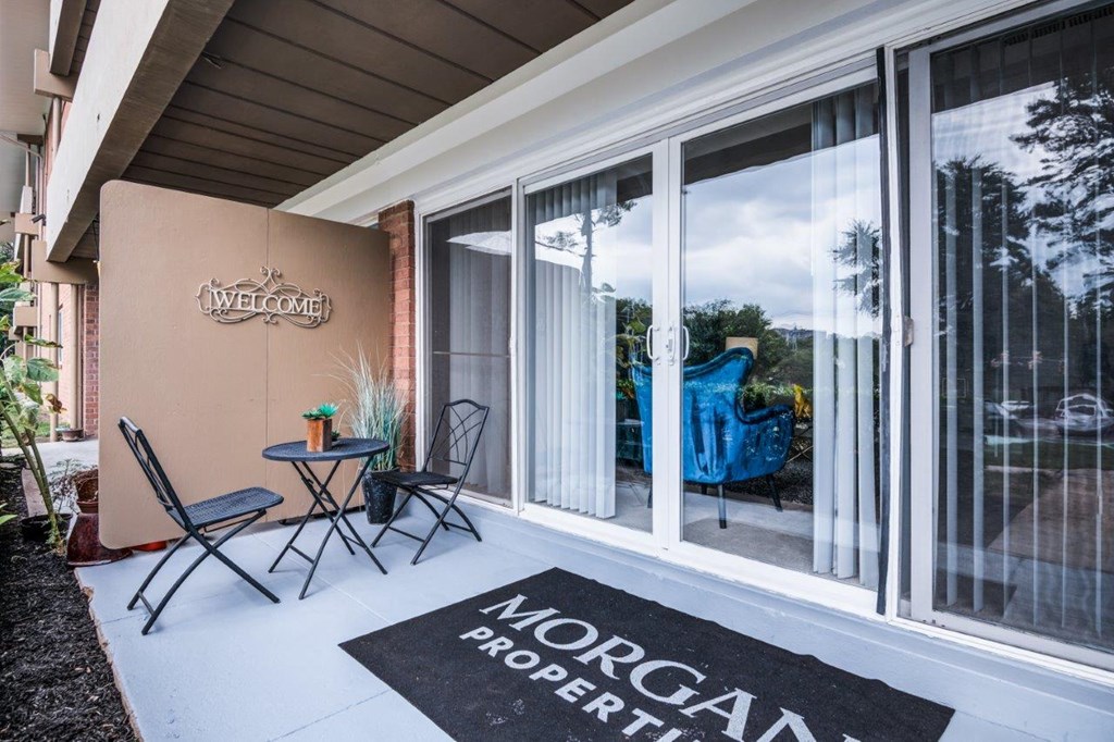 a patio with chairs and a rug in front of a house