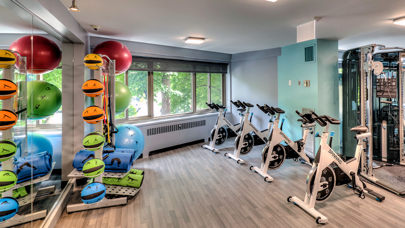 Inside one of the fitness centers at 1350-1360 Lake Shore Drive. Mirrors line the left wall with an exercise ball set in front. Spin bikes run along the right with windows at the far wall.