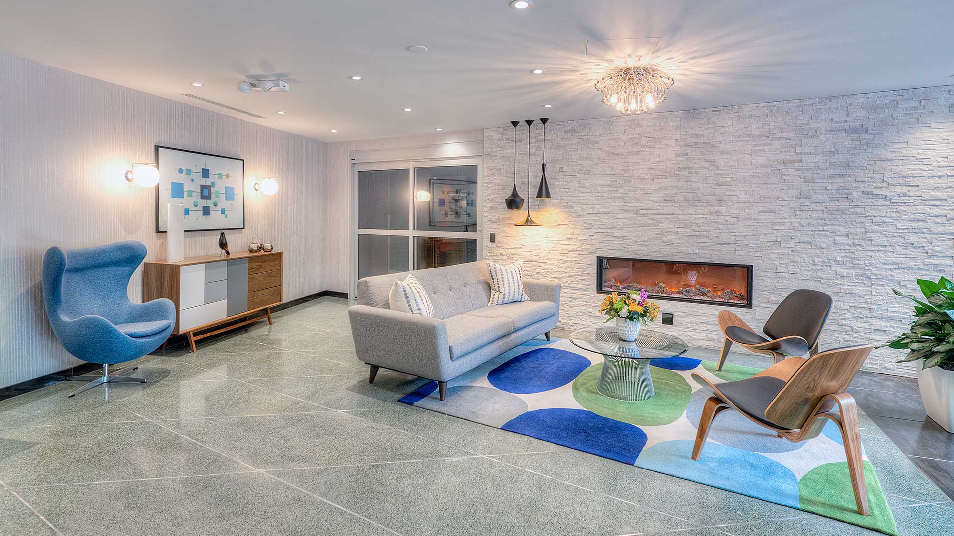 The lounge area in the 1350 Lake Shore Drive lobby. A couch and chairs sit on an area rug before a built-in fireplace. Off to the left is the entrance to the private residences.