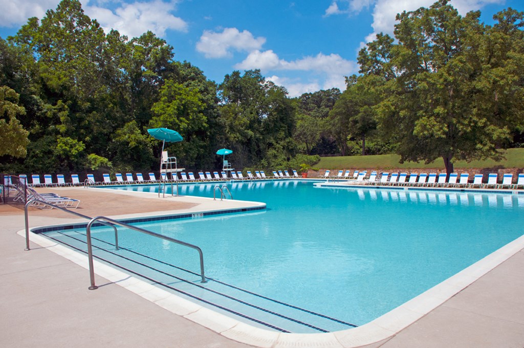 a swimming pool with chairs and umbrellas at a resort