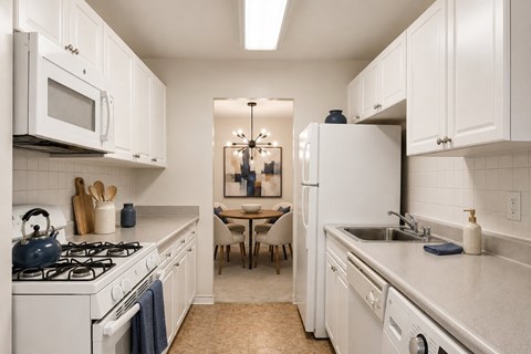 A kitchen with white cabinets and a white stove top oven.