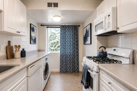 A kitchen with white cabinets and a black and white patterned curtain.