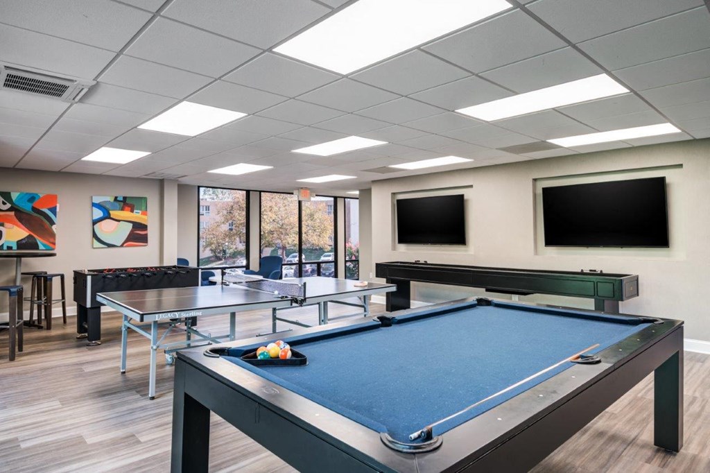 a games room with a pool table and two televisions
