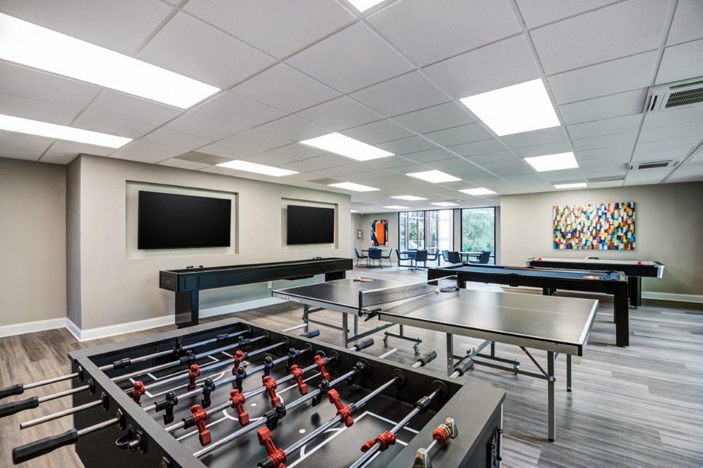 a game room with ping pong tables and televisions