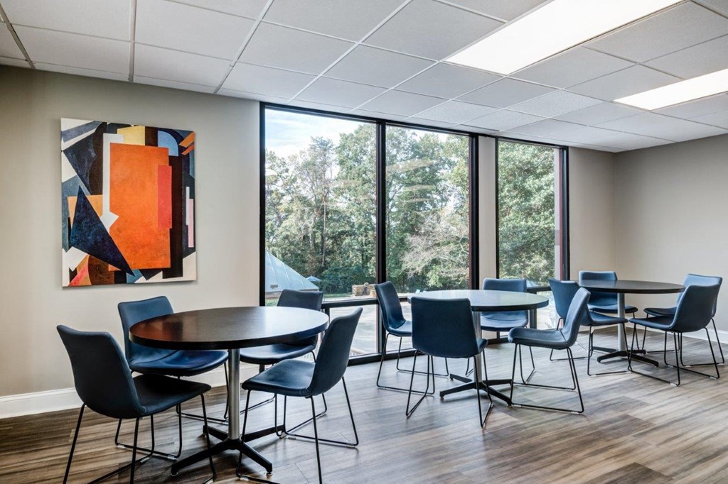 a dining room with tables and chairs and a painting on the wall