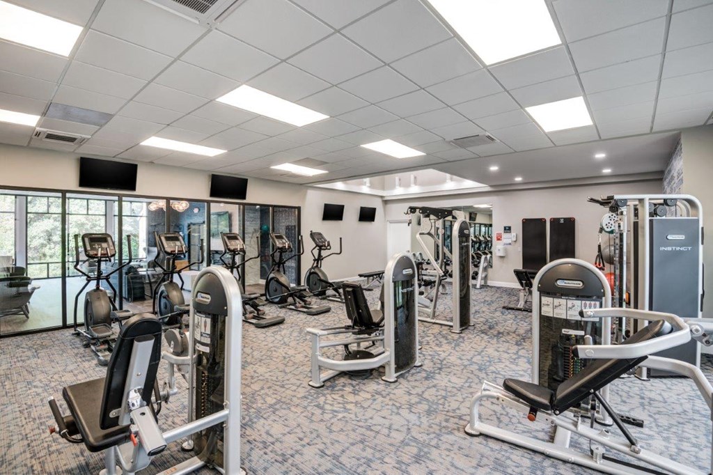 a gym with weights and cardio equipment in a room with windows