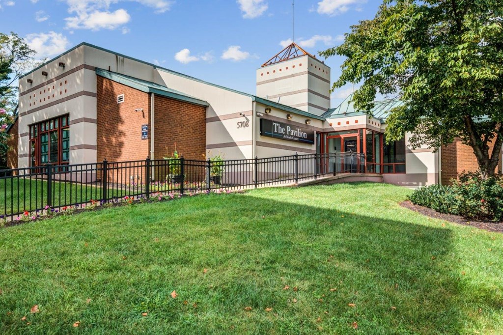 the front of a building with a lawn and a fence
