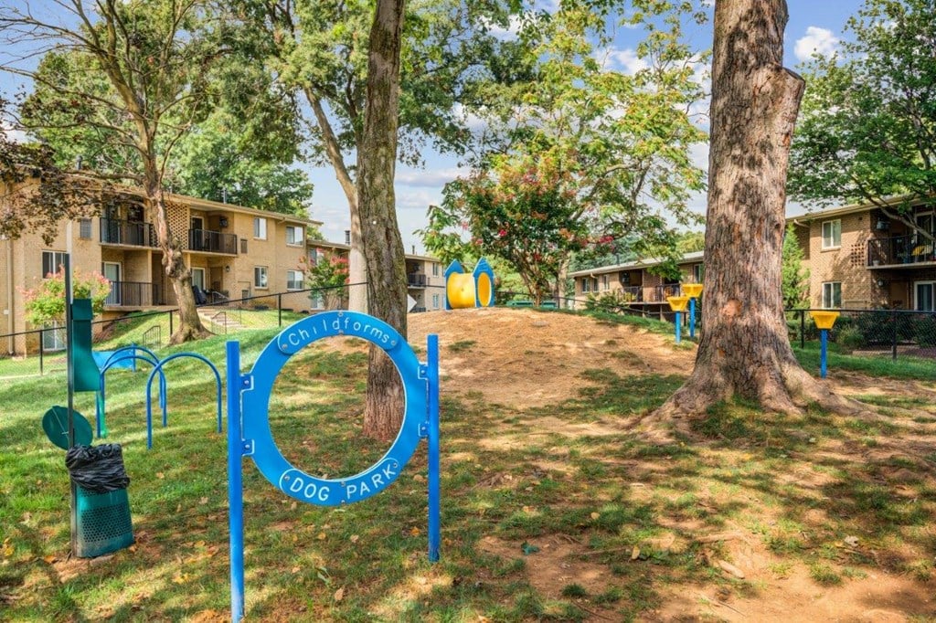 a park with a playground and trees with apartments in the background