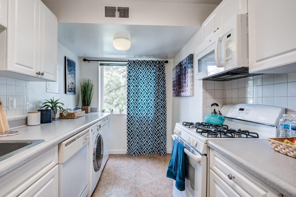 a white kitchen with a washer and dryer and a window