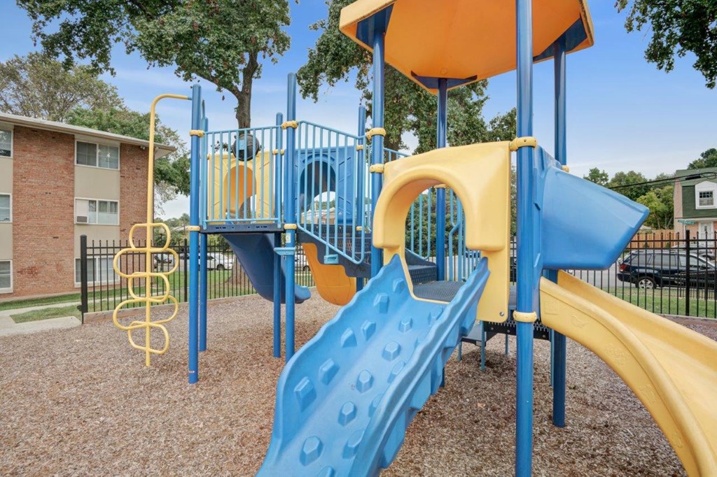 a playground with a blue and yellow slide      and a swing
