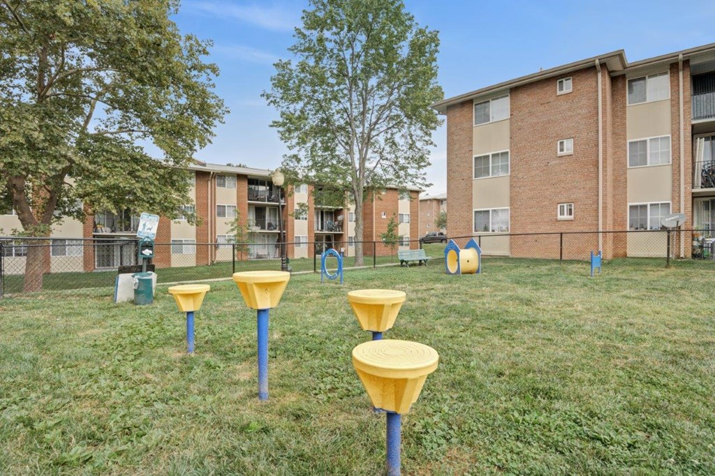 a yard with yellow stools in front of an apartment building