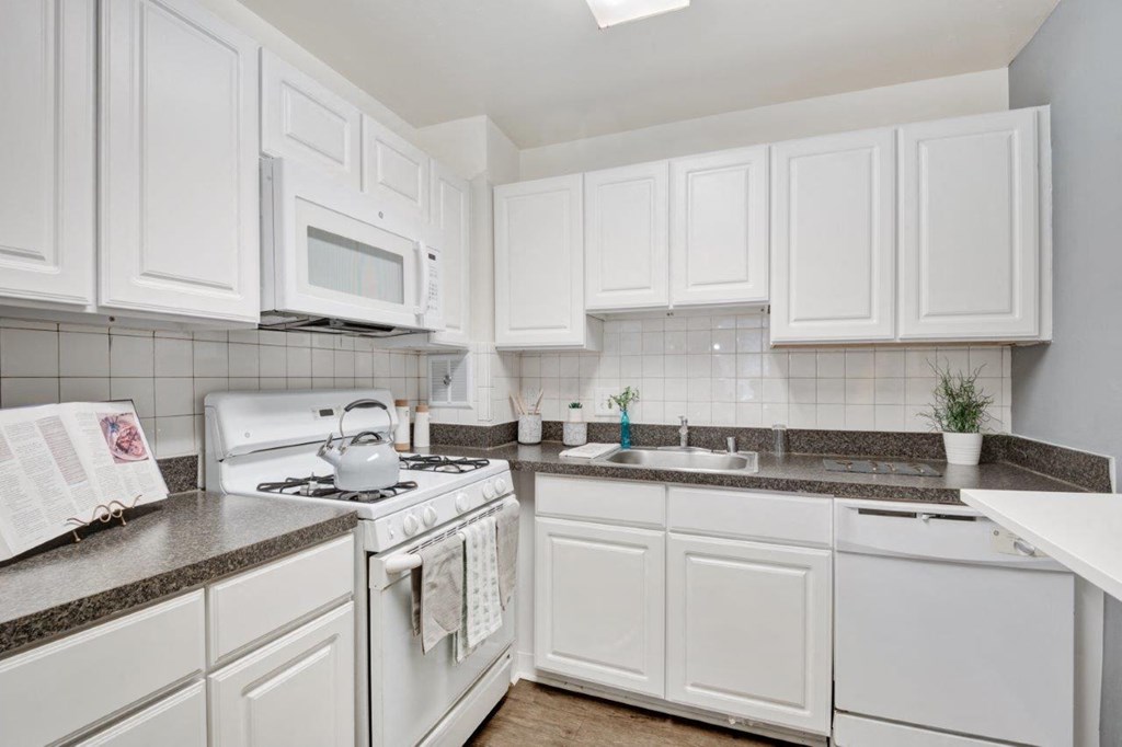 a kitchen with white cabinets and a stove and a sink