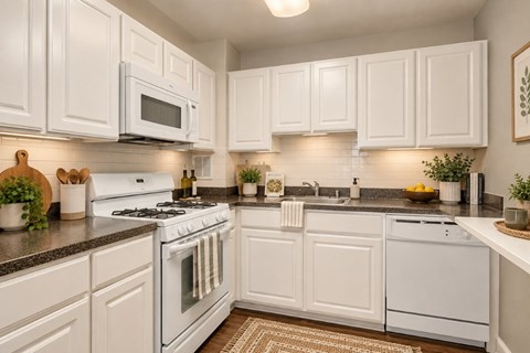 A white kitchen with a stove, microwave, and oven.