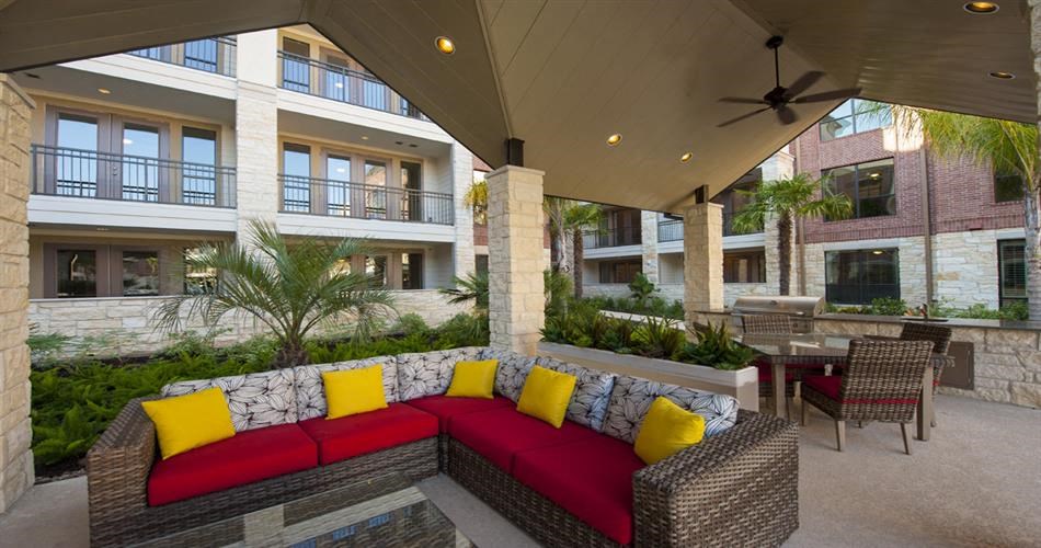 a patio with a red couch and yellow pillows