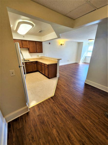 an empty kitchen with wooden floors and a refrigerator