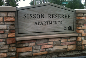 a stone sign apartments on a brick building