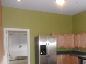 a kitchen with green walls and a stainless steel refrigerator