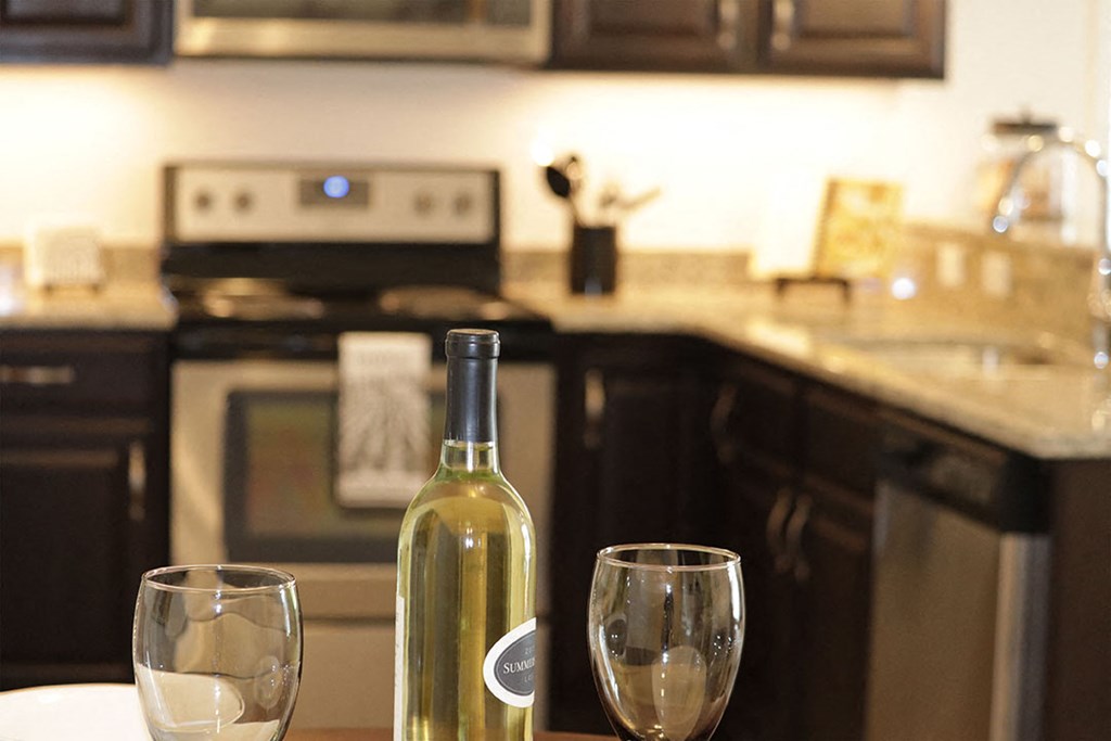 a bottle of wine and two wine glasses on a kitchen counter