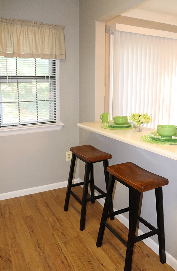a kitchen with two bar stools and a counter with bowls and plates on it