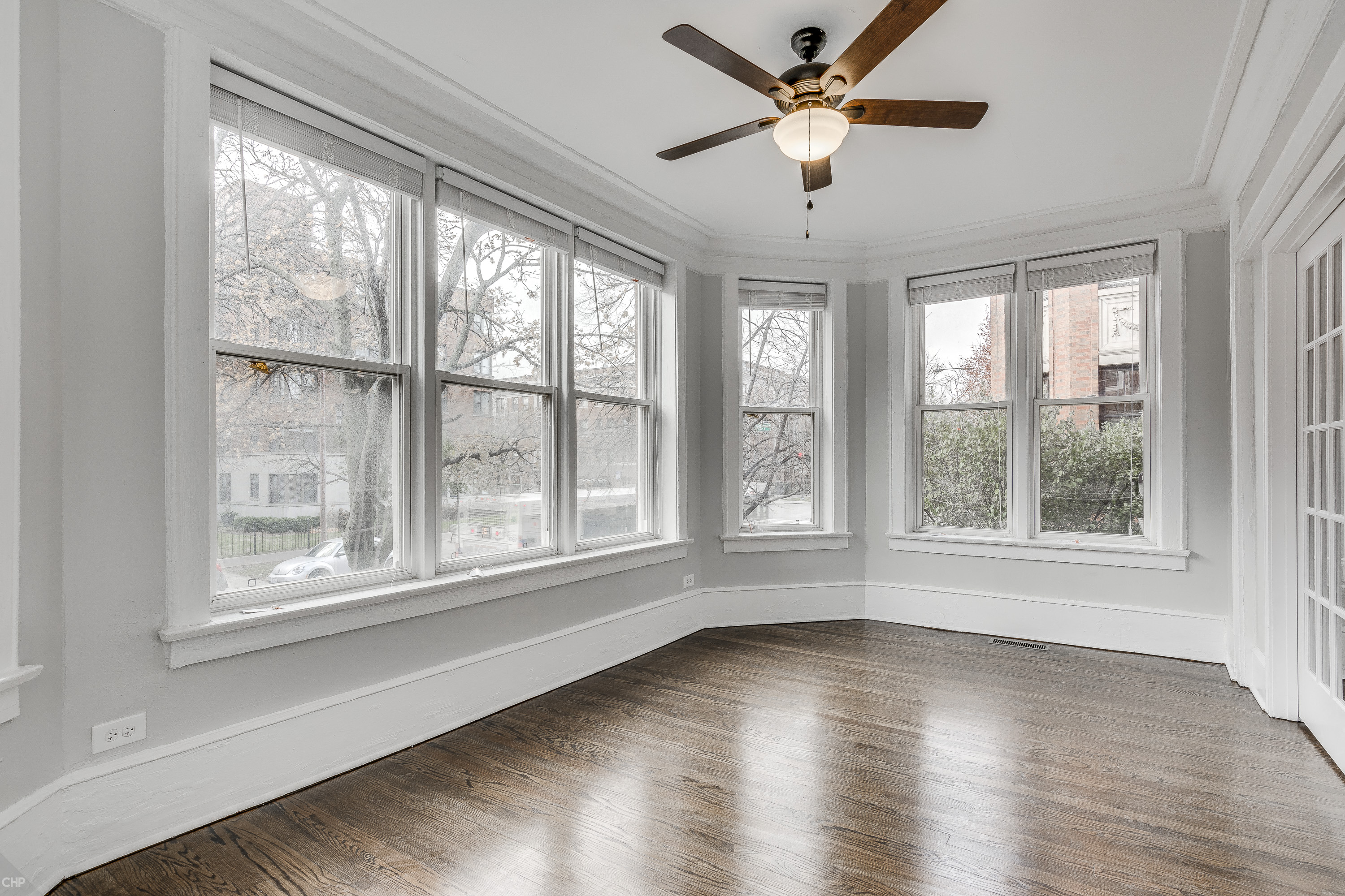an empty living room with a ceiling fan and six windows